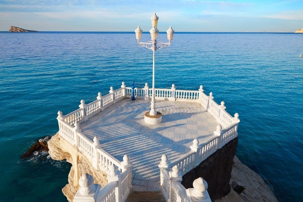 a white balcony with a lamp post in the middle of the ocean