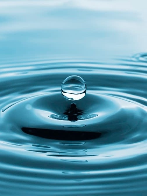 uma gota de água está caindo na superfície da água .