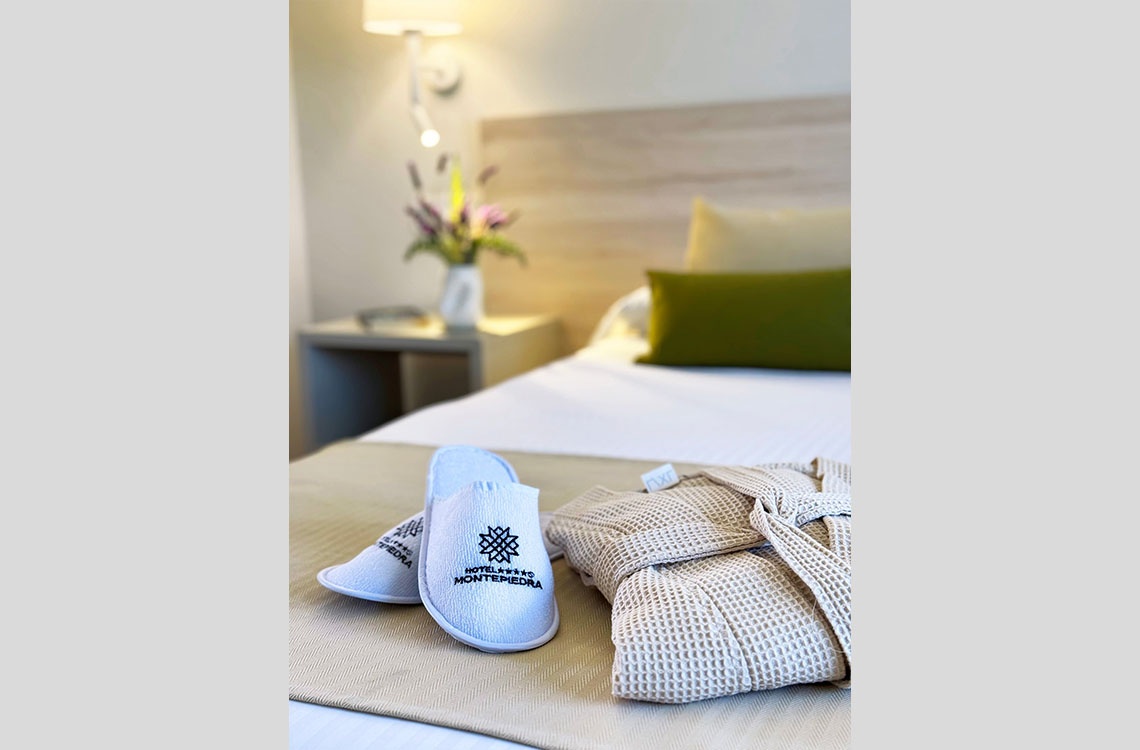 Espectaculares amenidades de hotel: zapatillas y bata de baño, con toques de 'Dynastic Corporativa'.