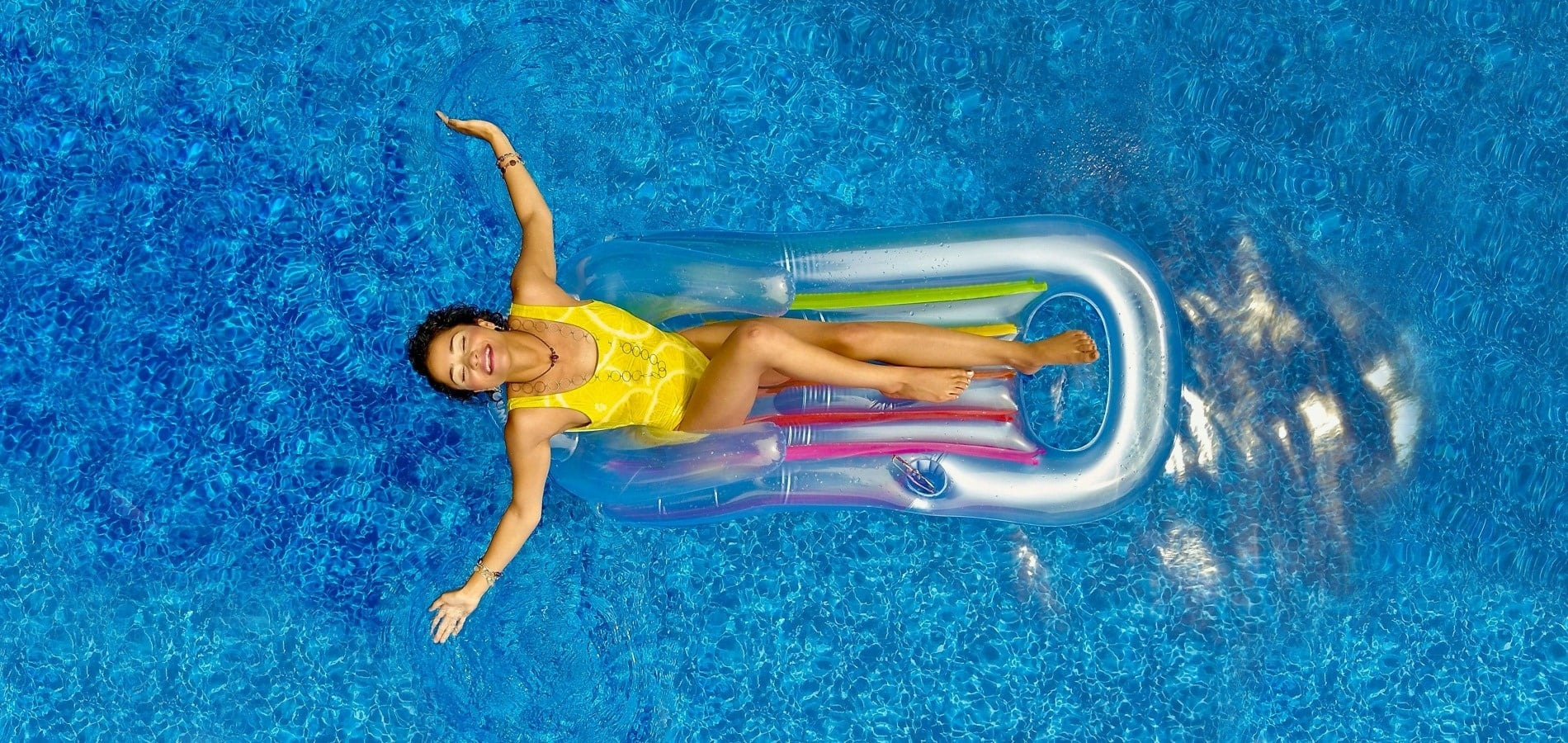 TEST4: Copia14: Woman relaxing on an inflatable mattress in a bright blue swimming pool.