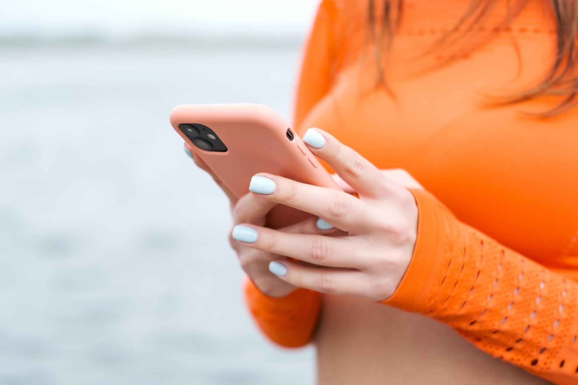 a woman in an orange shirt is using her phone