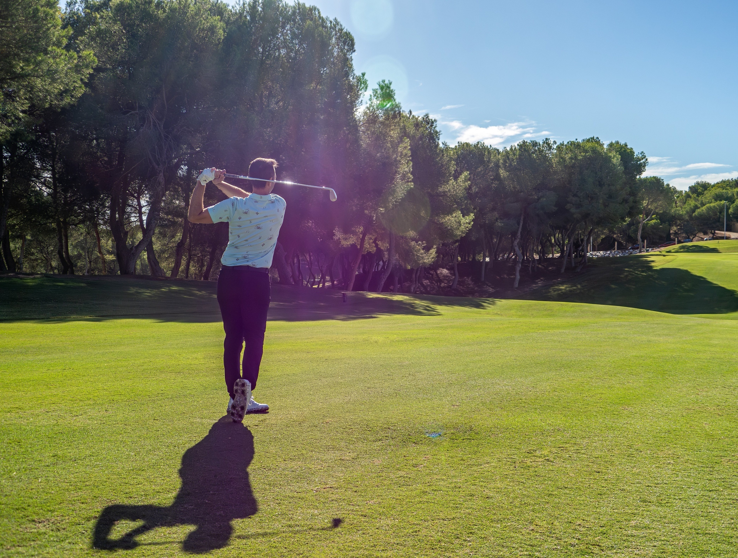 a man swings a golf club on a golf course