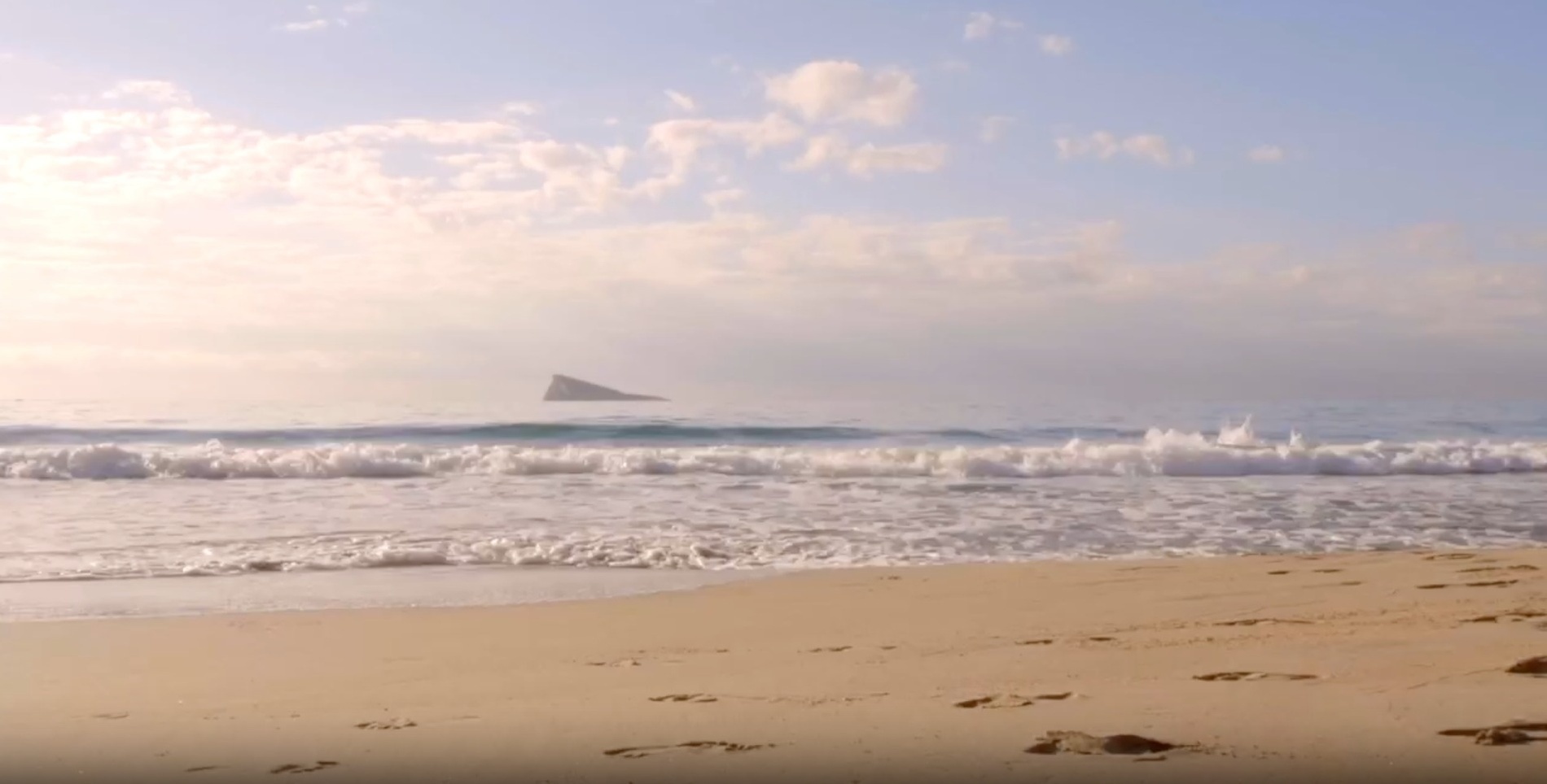 una playa vacía con un edificio en la distancia