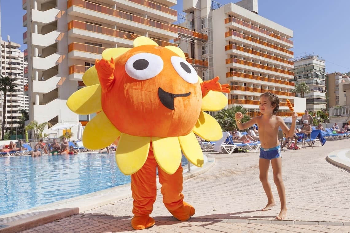 um menino está ao lado de uma mascote laranja e amarela