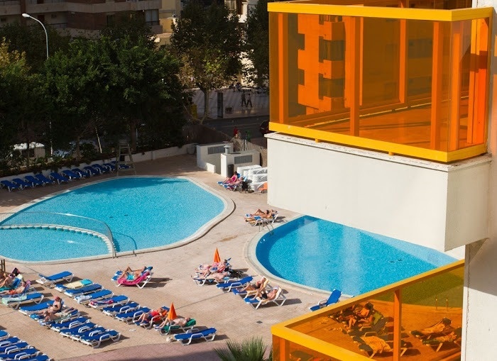a large swimming pool is surrounded by chairs and umbrellas