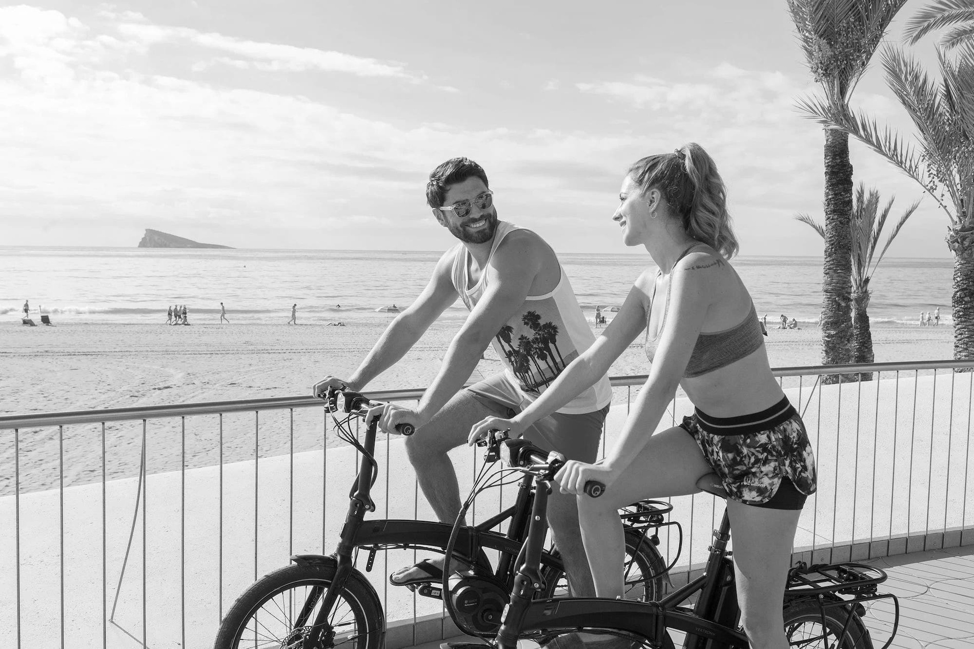 um homem e uma mulher estão andando de bicicleta na praia=s1900