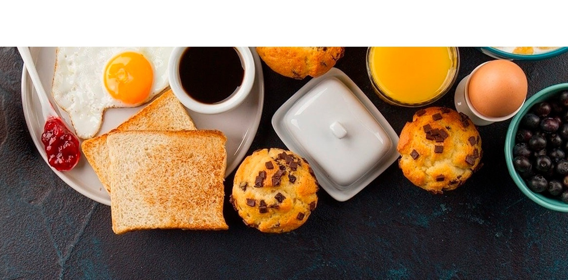 un desayuno con huevos fritos tostadas muffins y arándanos