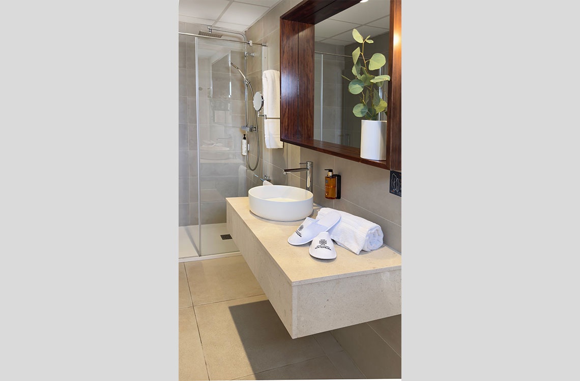 Bañera moderna con zapatillas y toalla, parte de la experiencia Dynastic Corporativa.