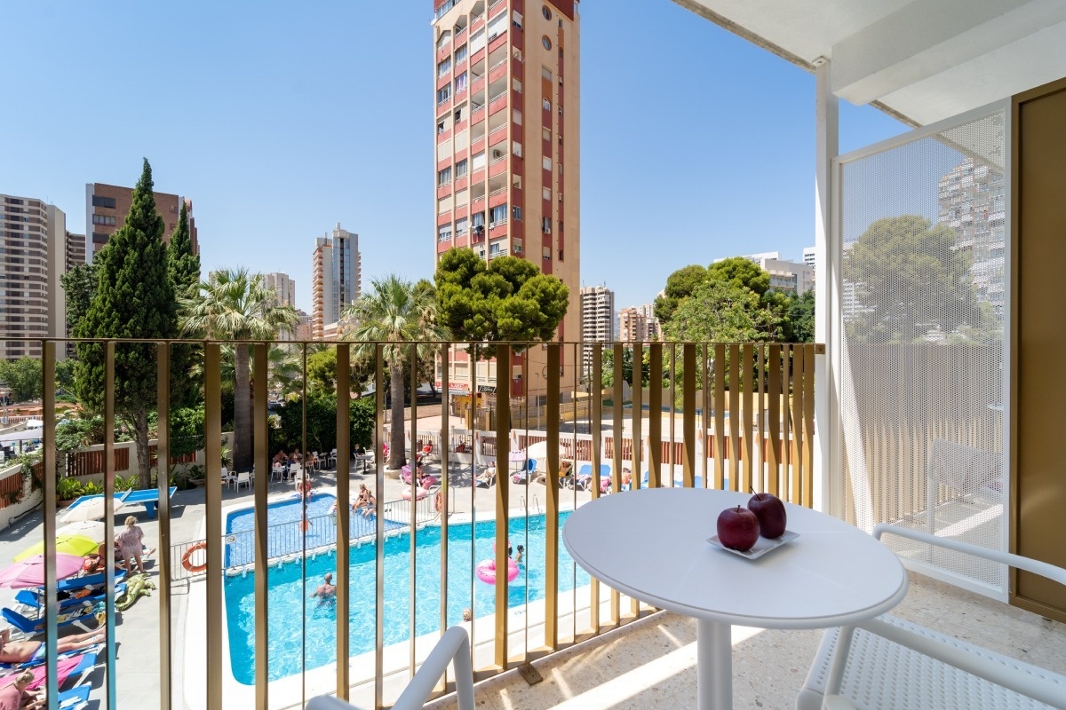 a balcony with a table and chairs overlooking a swimming pool