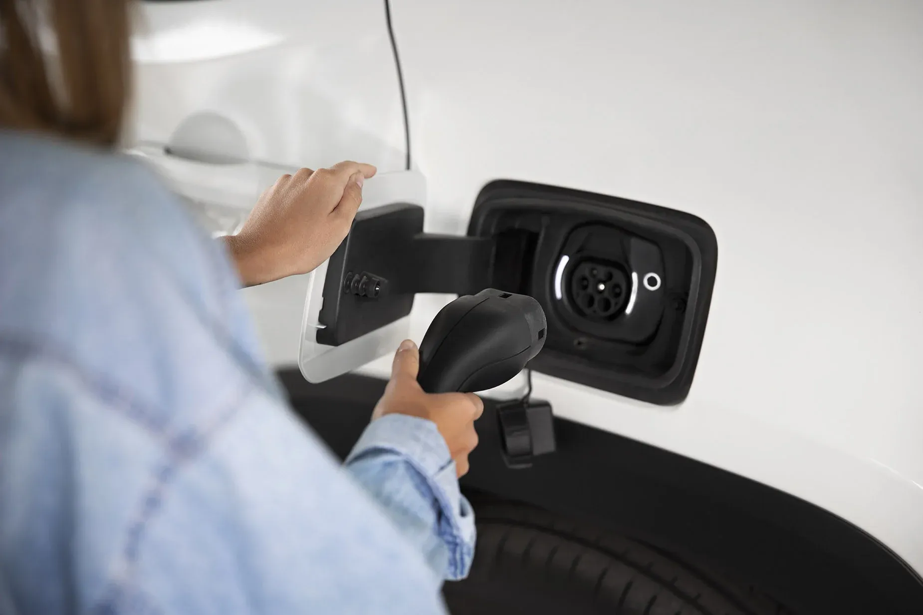 Dynastic Resorts: mano sujetando cargador de vehículo eléctrico, estaciones de carga.