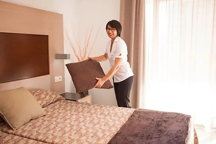 a woman is holding a brown pillow in a hotel room