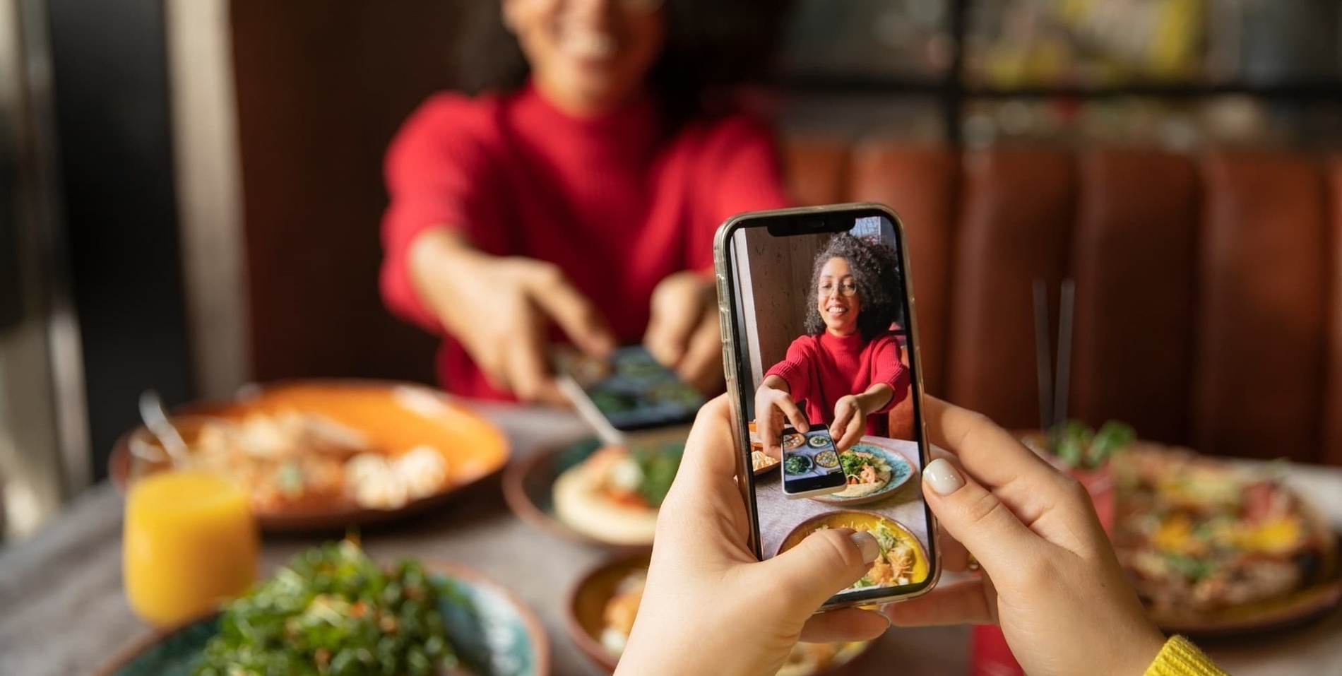 una persona sostiene un teléfono inteligente frente a una mesa de comida