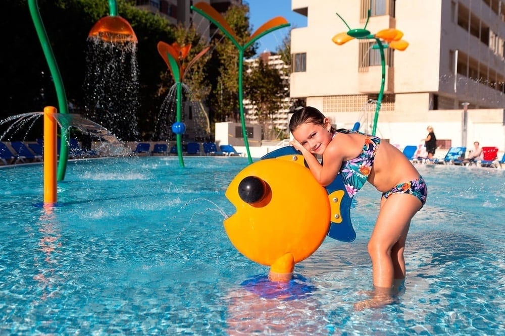 a little girl playing with a fish in a pool