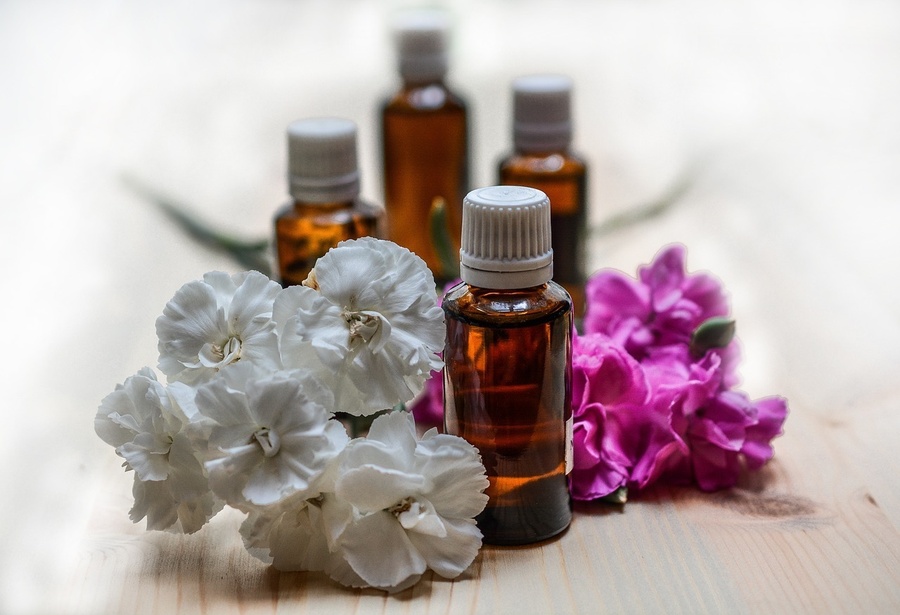 a bottle of essential oil sits next to a bunch of flowers