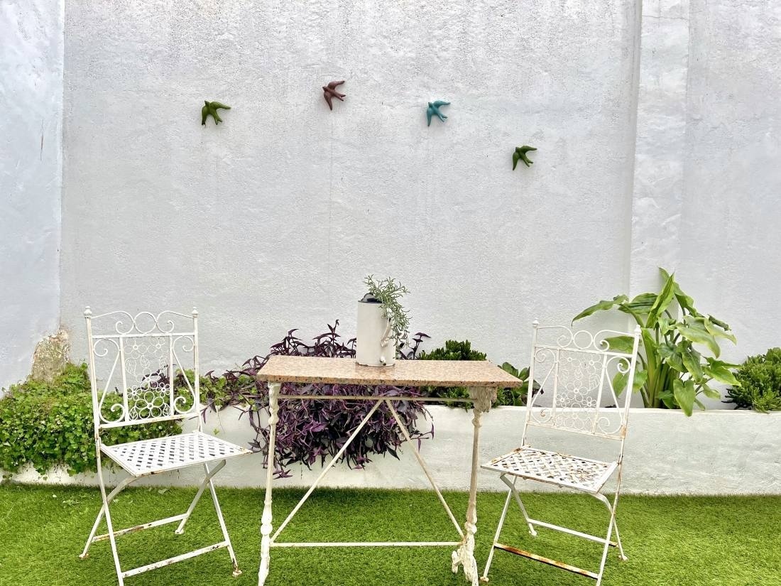 a table and chairs in front of a white wall with birds on it