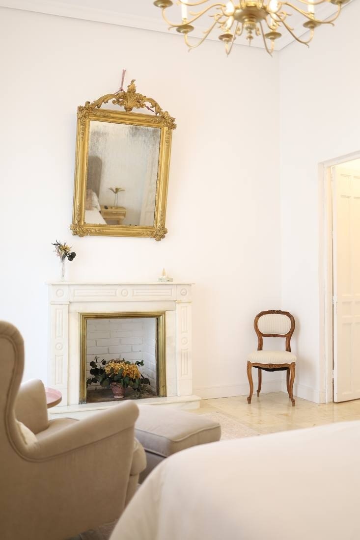 a living room with a fireplace a chair and a mirror