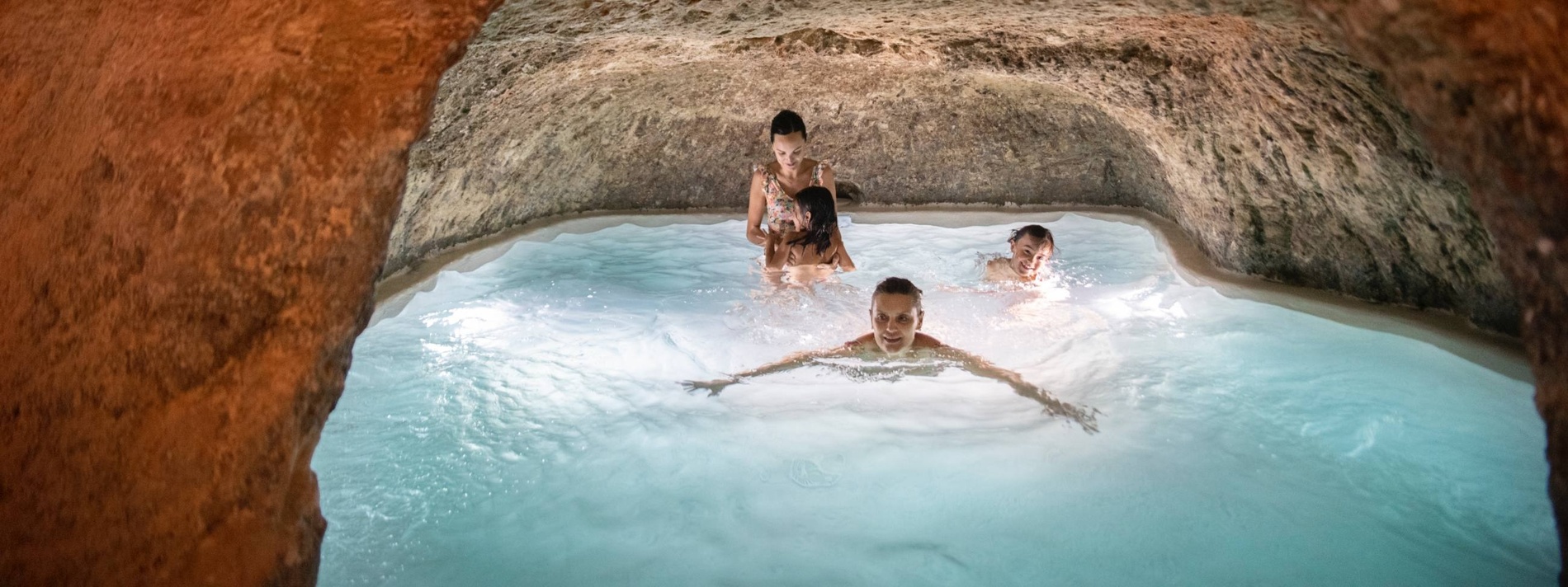 a group of people are swimming in a pool in a cave
