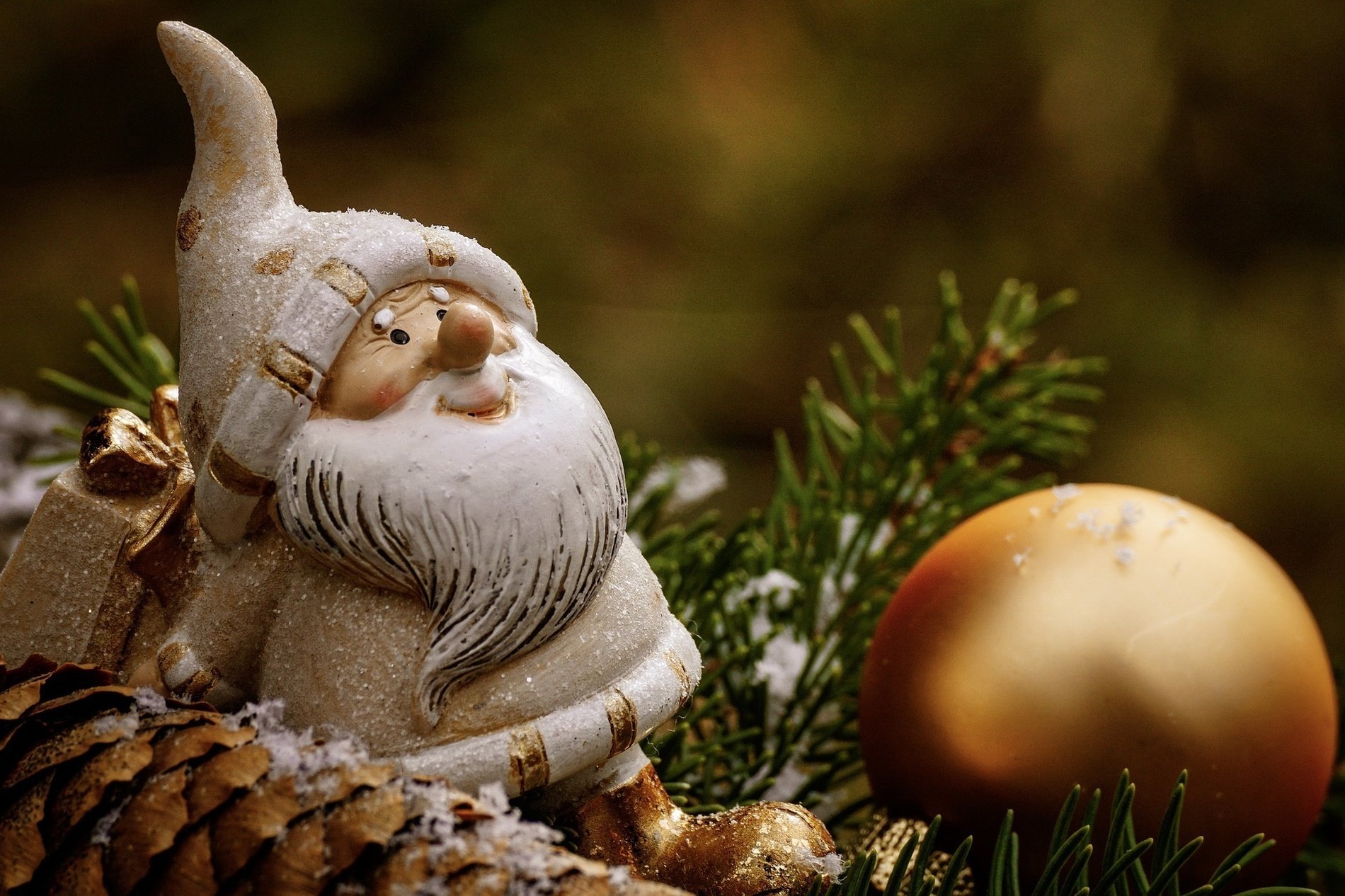 una estatua de santa claus está sentada en un cono de pino junto a una bola de navidad