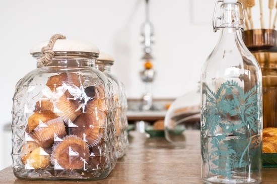 a jar of muffins sits on a table next to a bottle