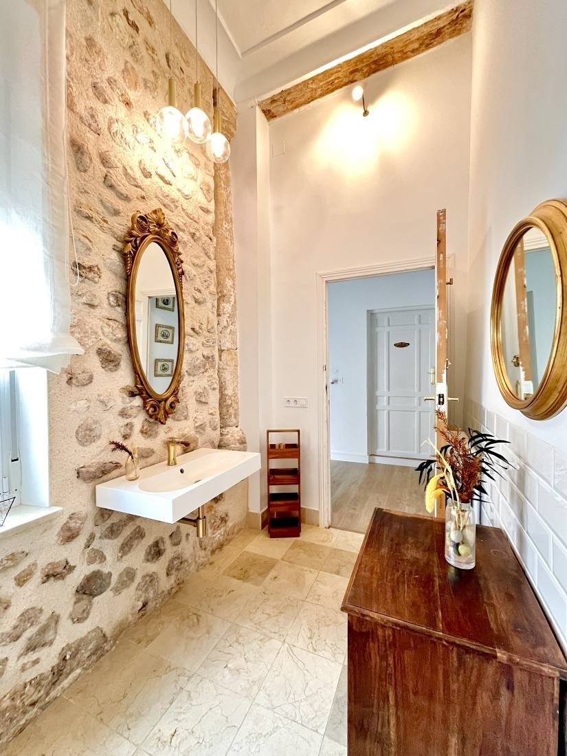 a bathroom with a stone wall a sink and two mirrors