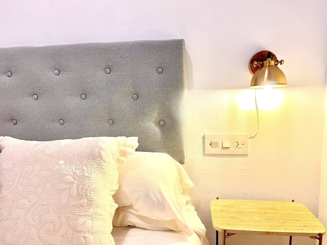 a bed with a grey headboard and white pillows