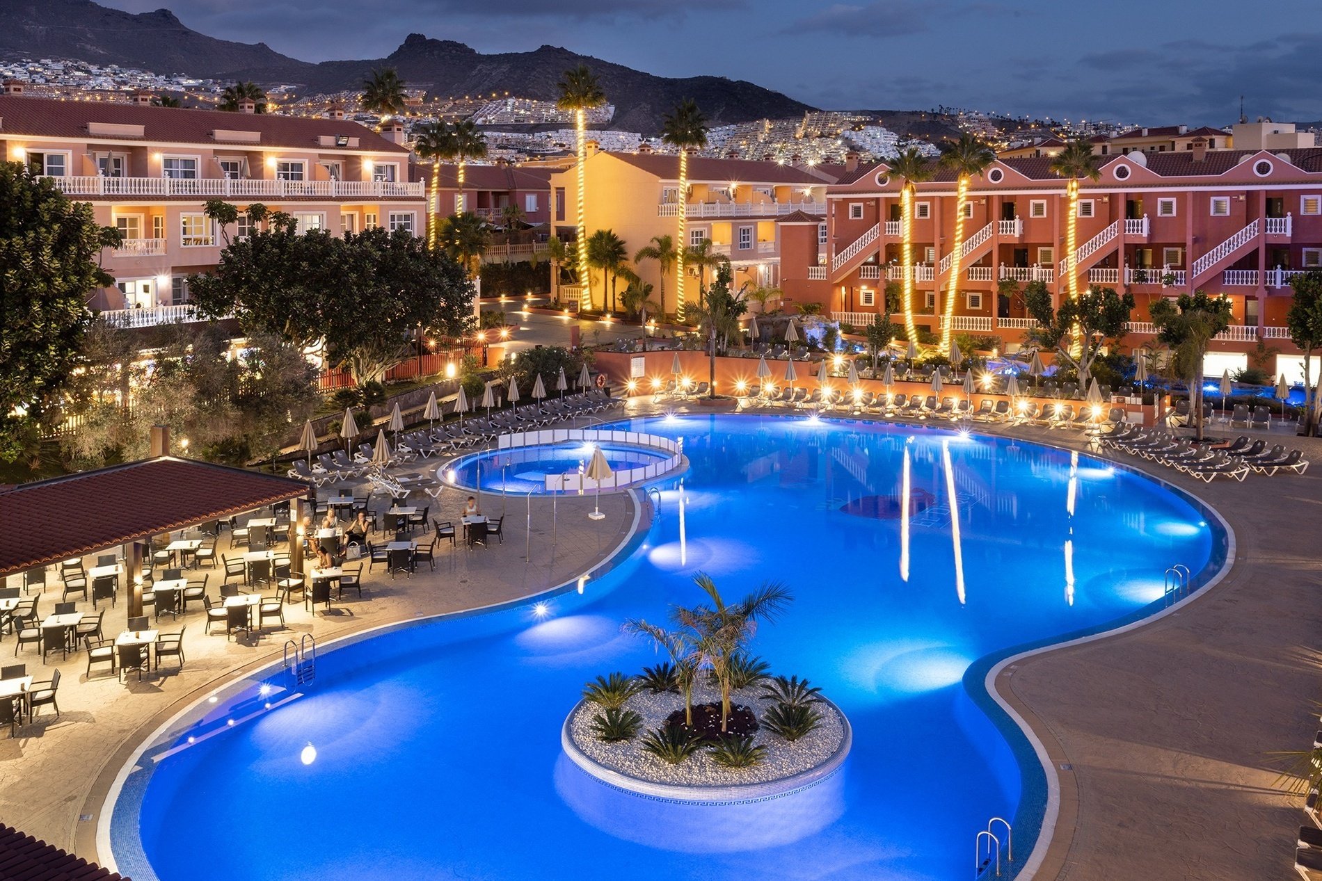 a large swimming pool is lit up at night