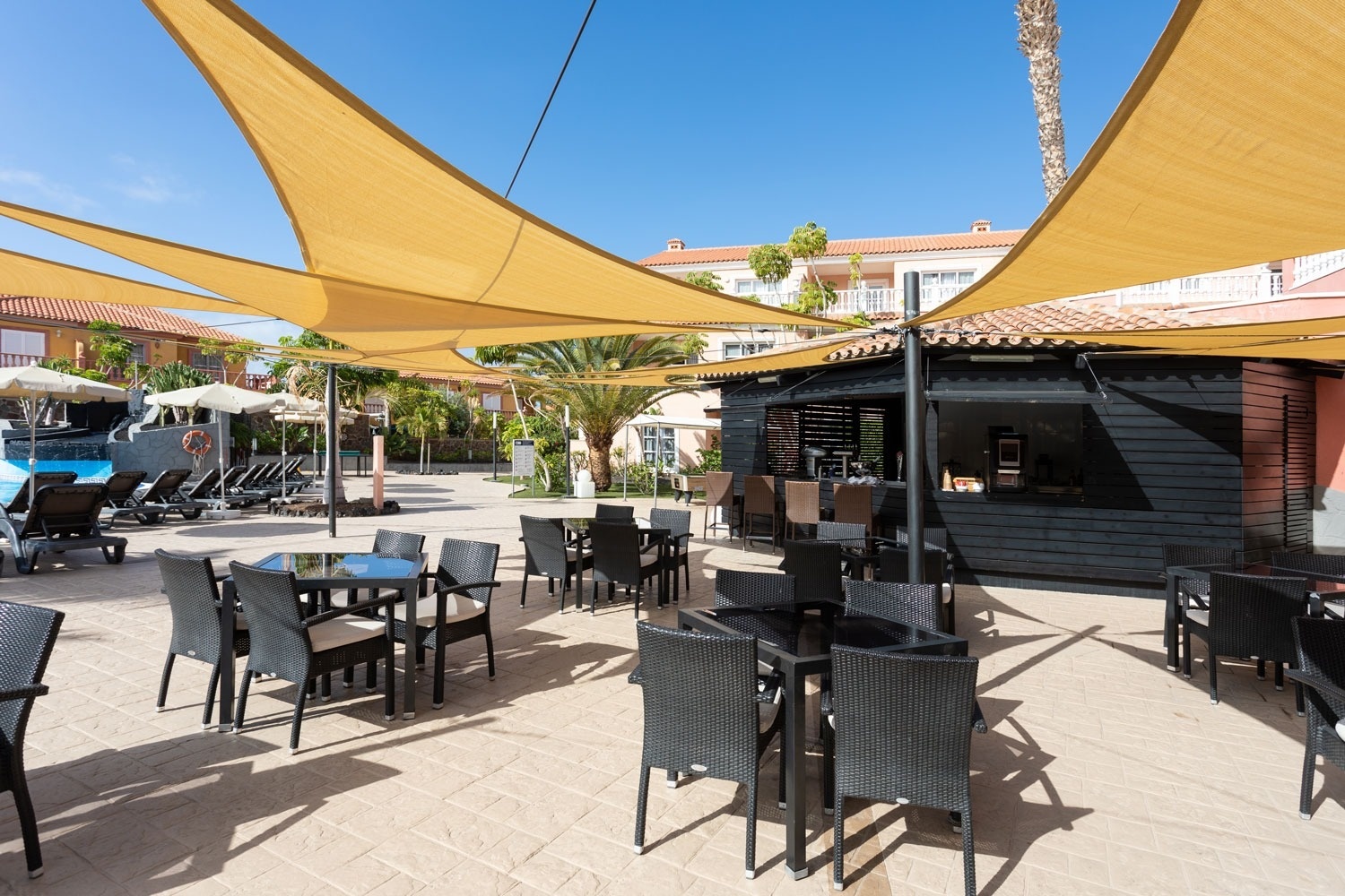 una zona de patio con mesas y sillas y sombrillas