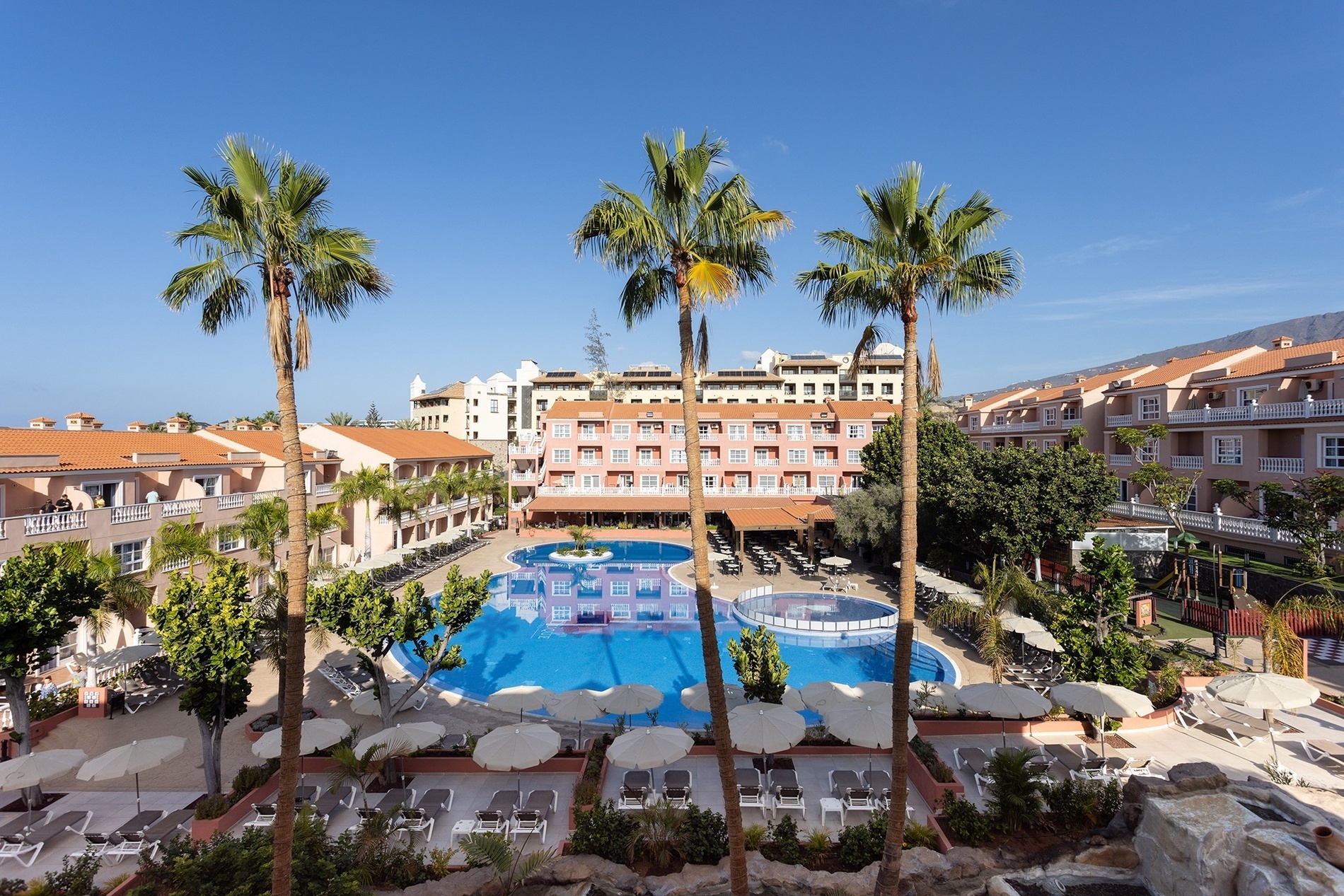 a large swimming pool is surrounded by palm trees and chairs