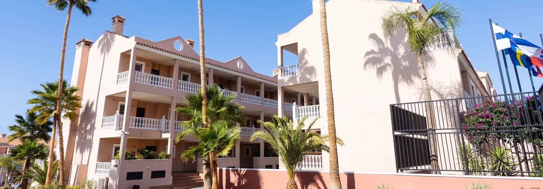 un edificio rosa con balcones y palmeras alrededor