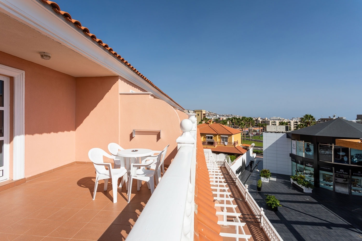 un balcón con una mesa y sillas y un edificio en el fondo