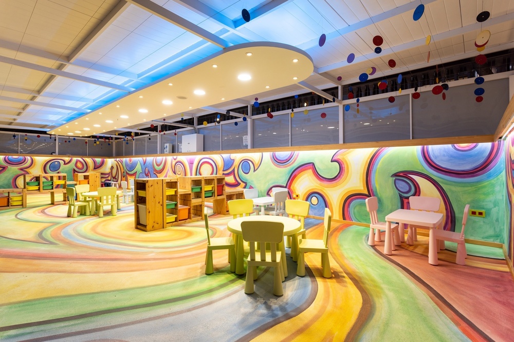 a children 's room with tables and chairs and a colorful wall