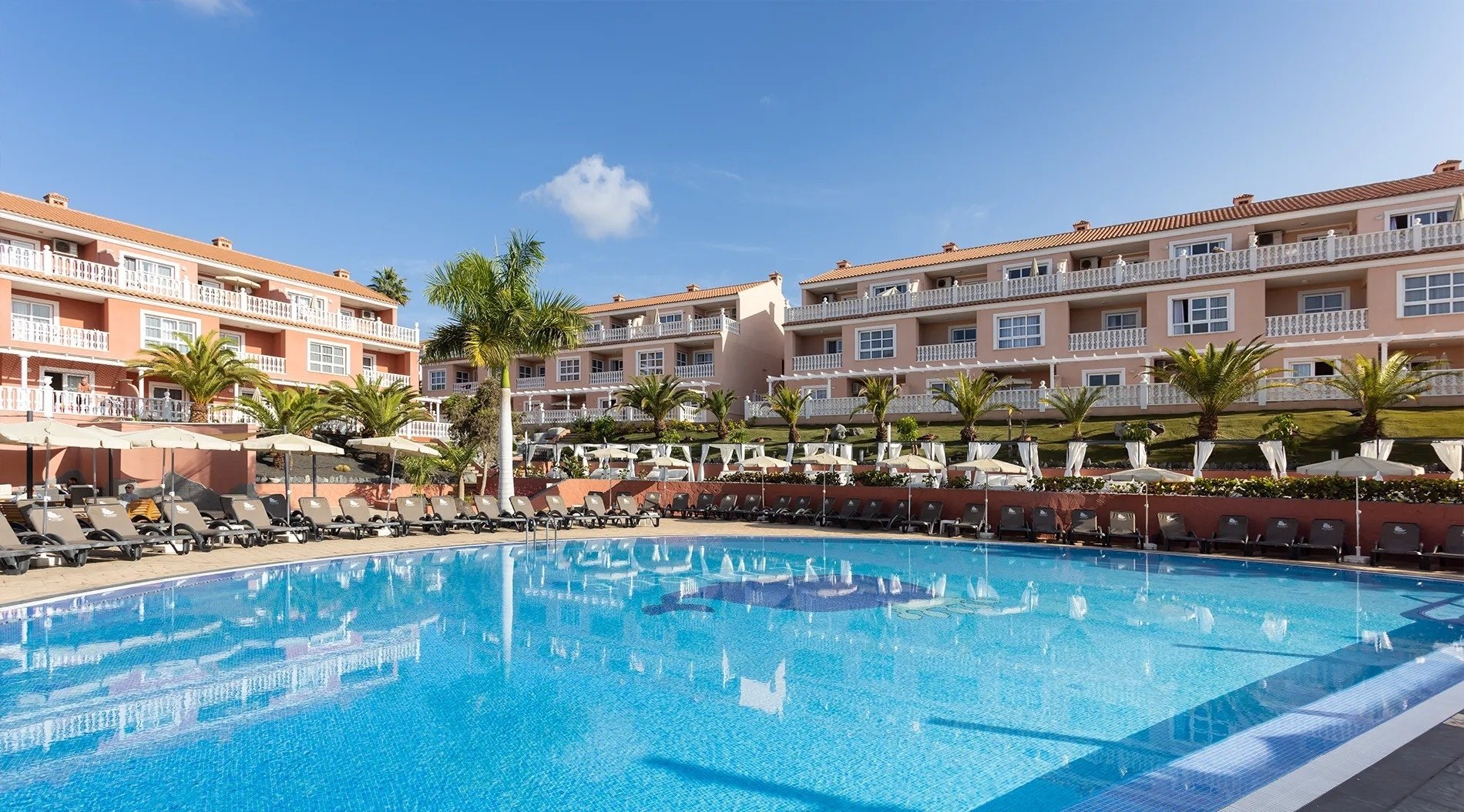 una piscina rodeada de sillas y sombrillas en un hotel