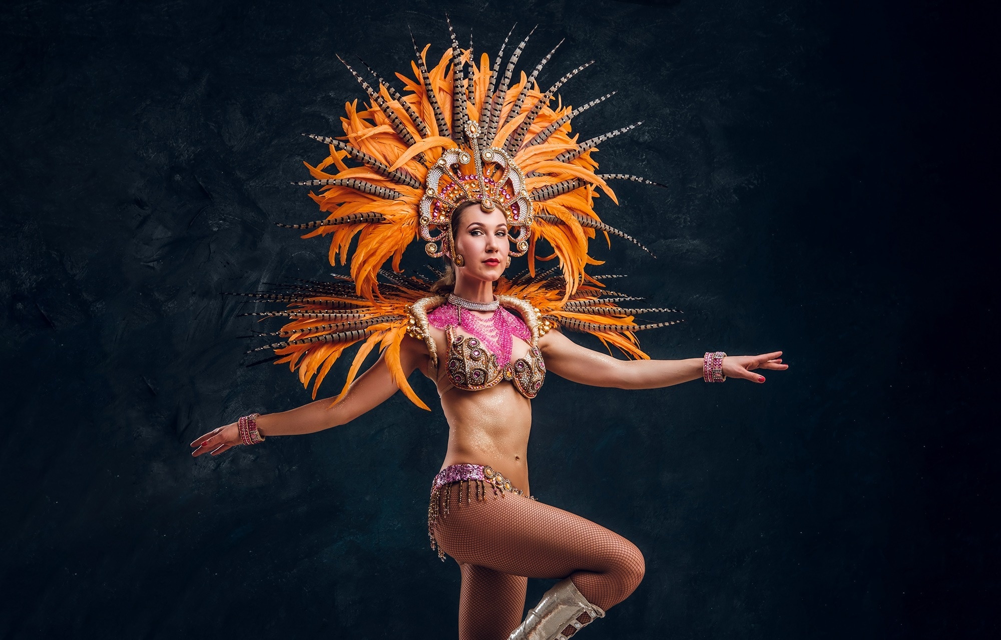 una mujer con un disfraz de carnaval con plumas naranjas y rosas