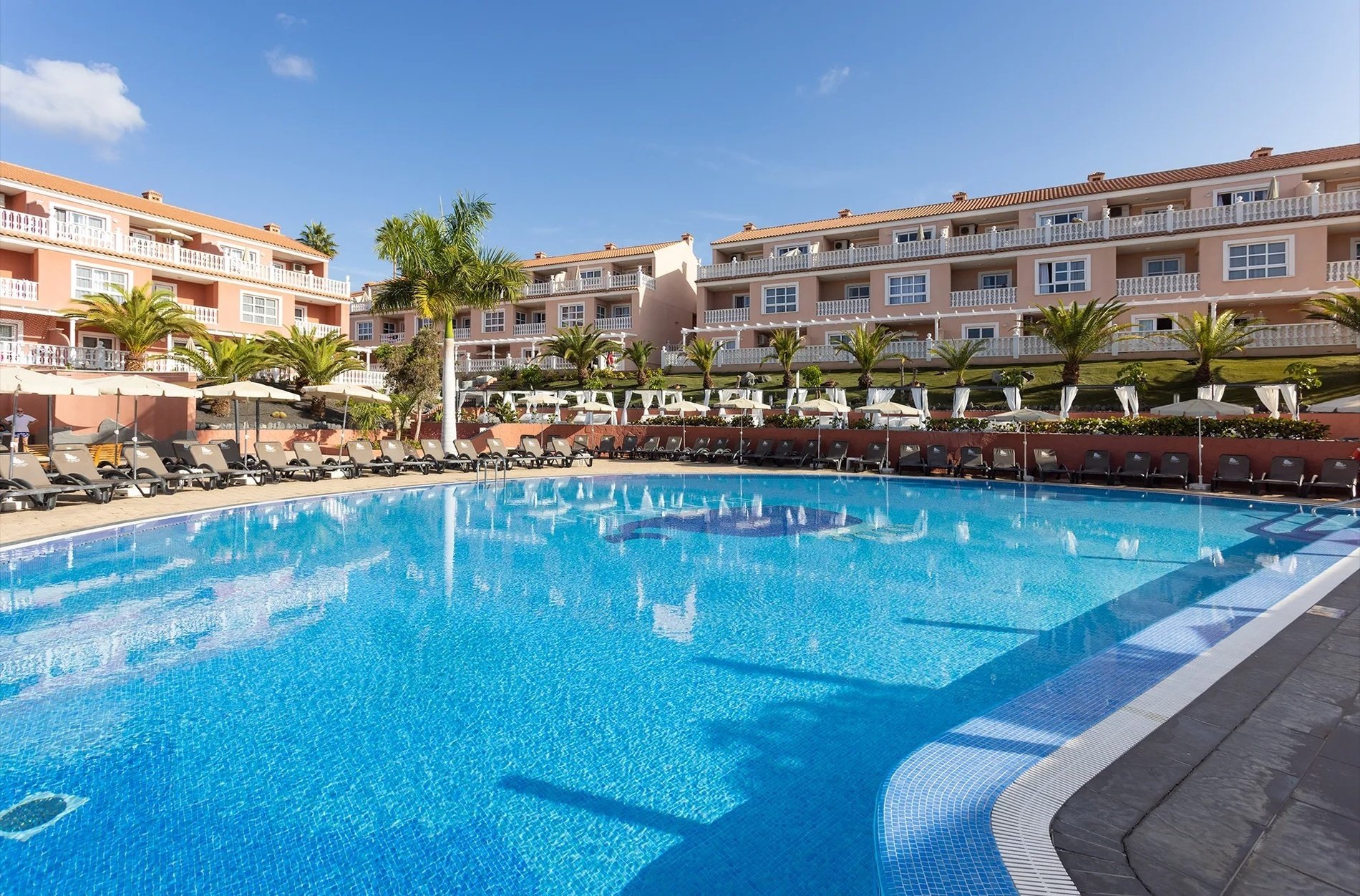 una gran piscina rodeada de sillas y sombrillas en un resort=s1900