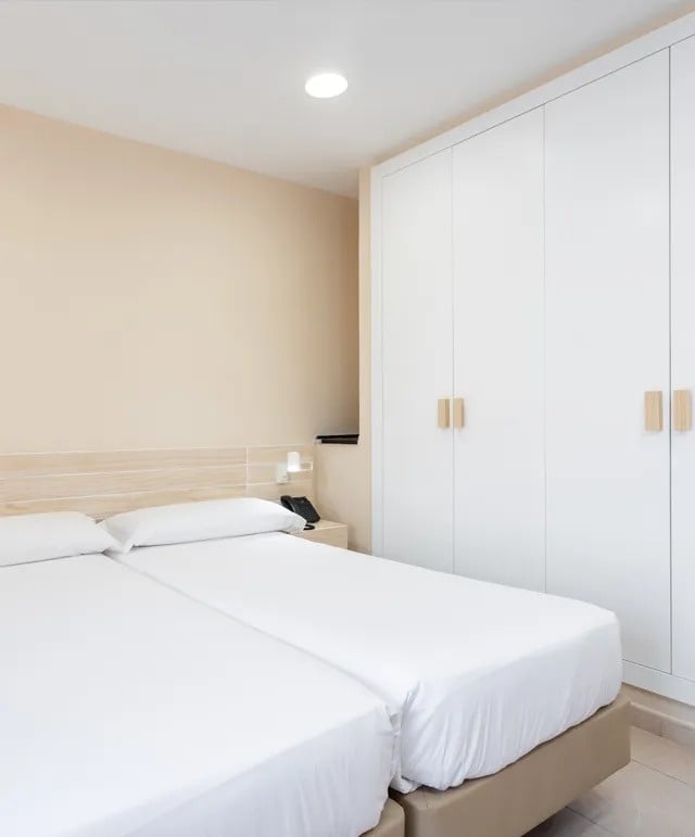 un dormitorio con dos camas y un armario blanco