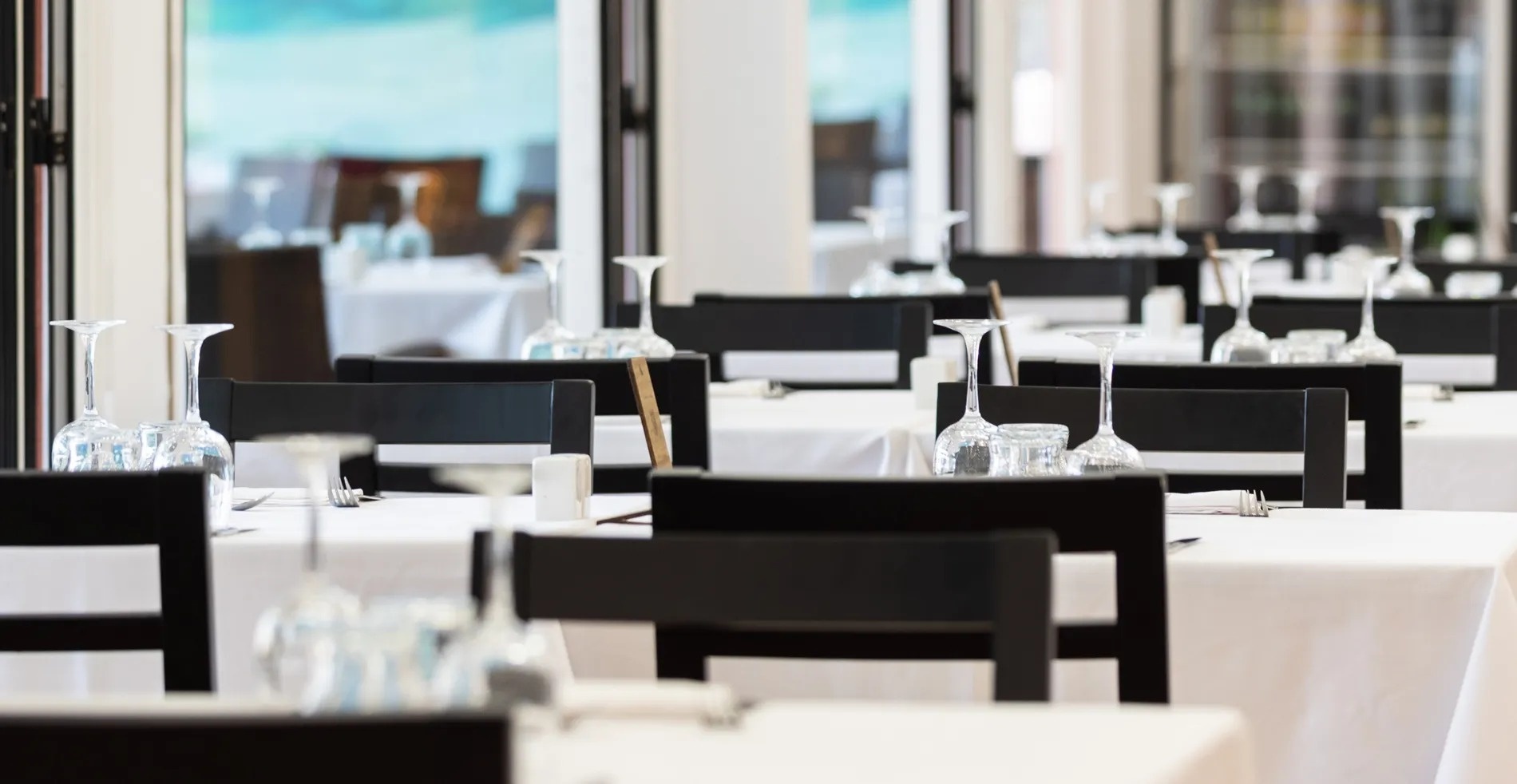 empty tables and chairs in a restaurant with wine glasses on them