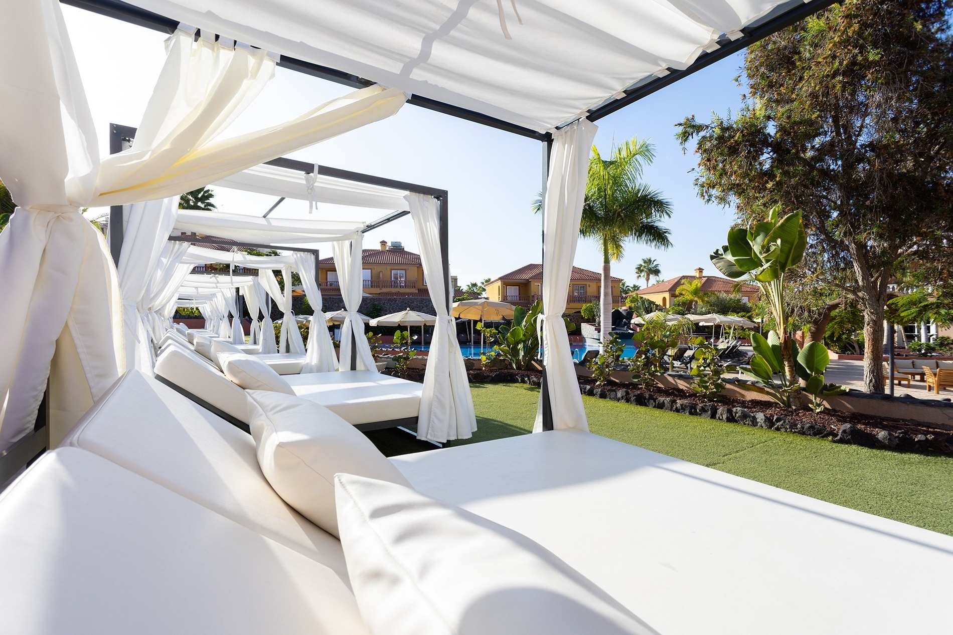 a row of white canopies are lined up in front of a swimming pool