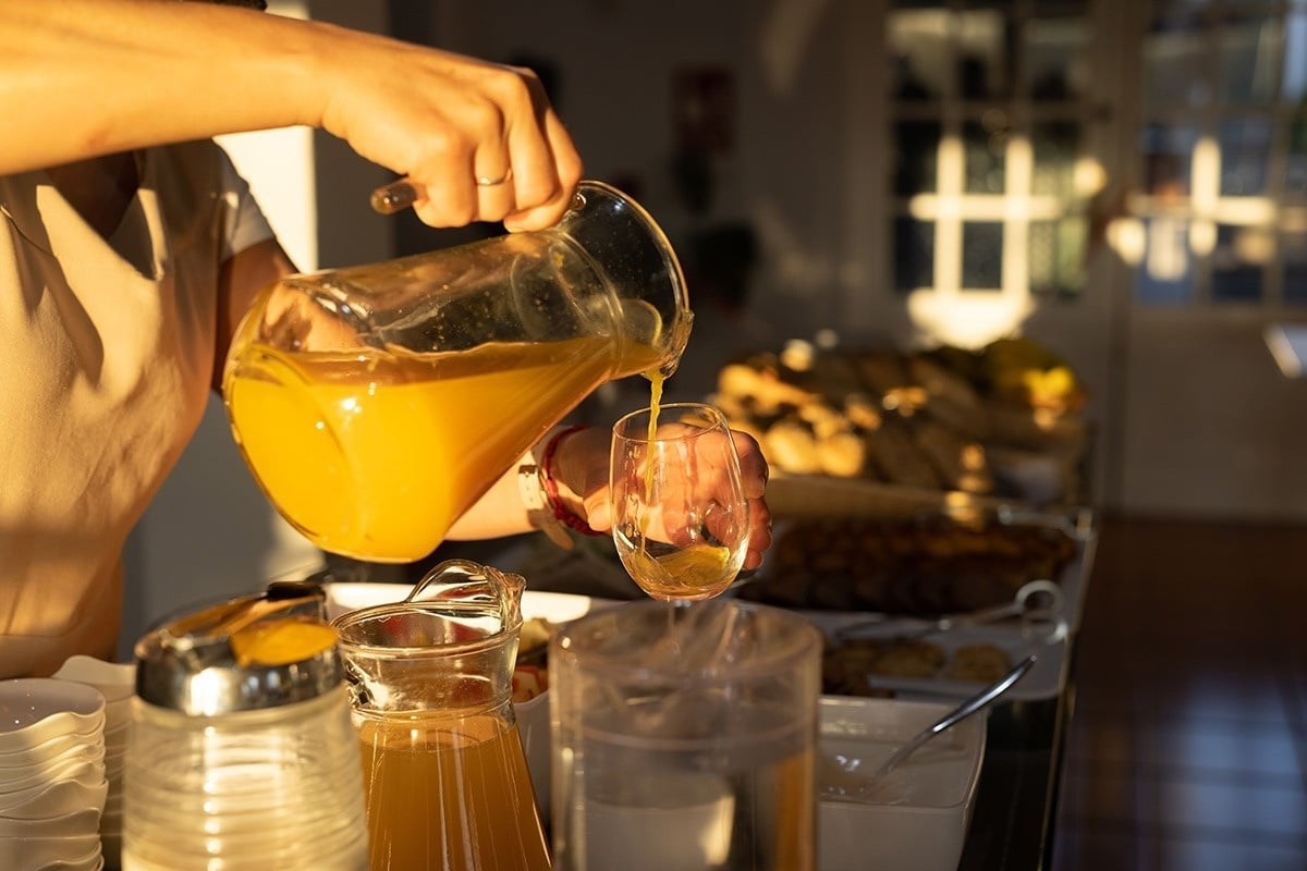 eine Person gießt Orangensaft in ein Glas