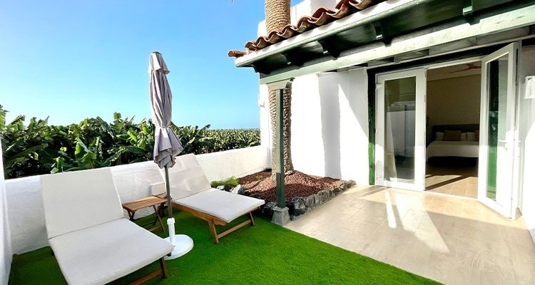 a patio with chairs and an umbrella with a bedroom in the background