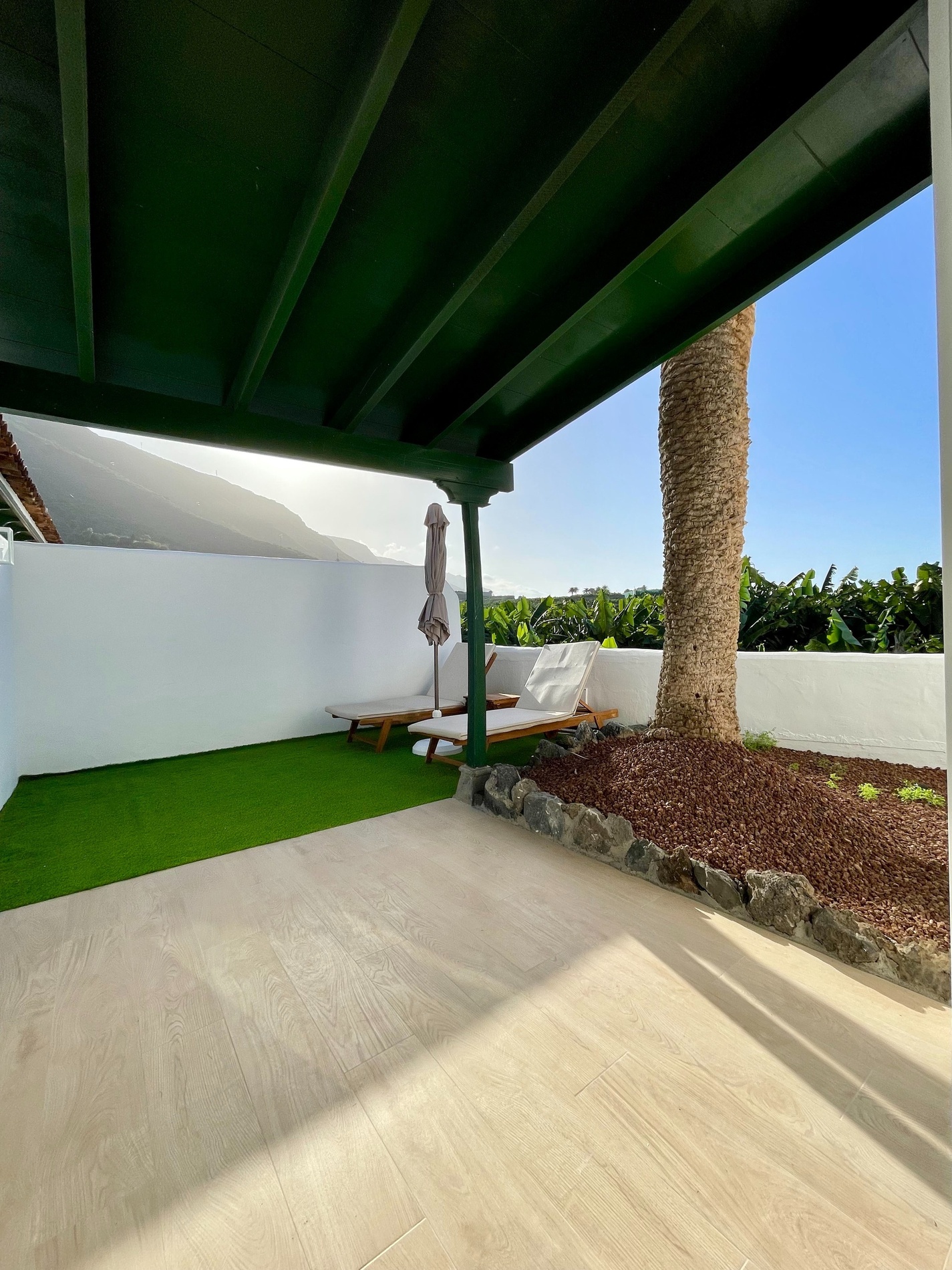 a patio with two lounge chairs and an umbrella