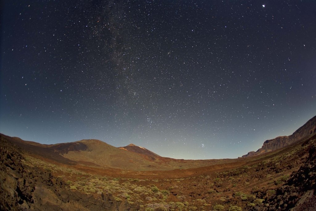 ein Nachthimmel mit vielen Sternen über einem Tal