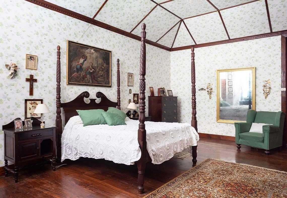 Bedroom with canopy bed, tapestry and patio view.