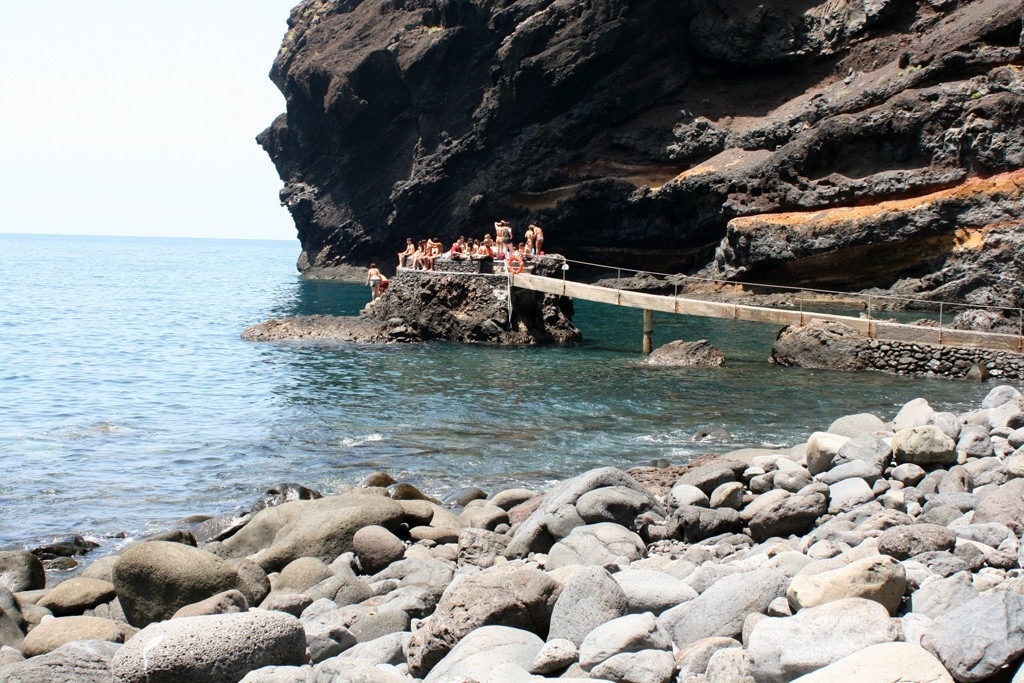 eine Gruppe von Menschen steht auf einer Brücke über den Ozean