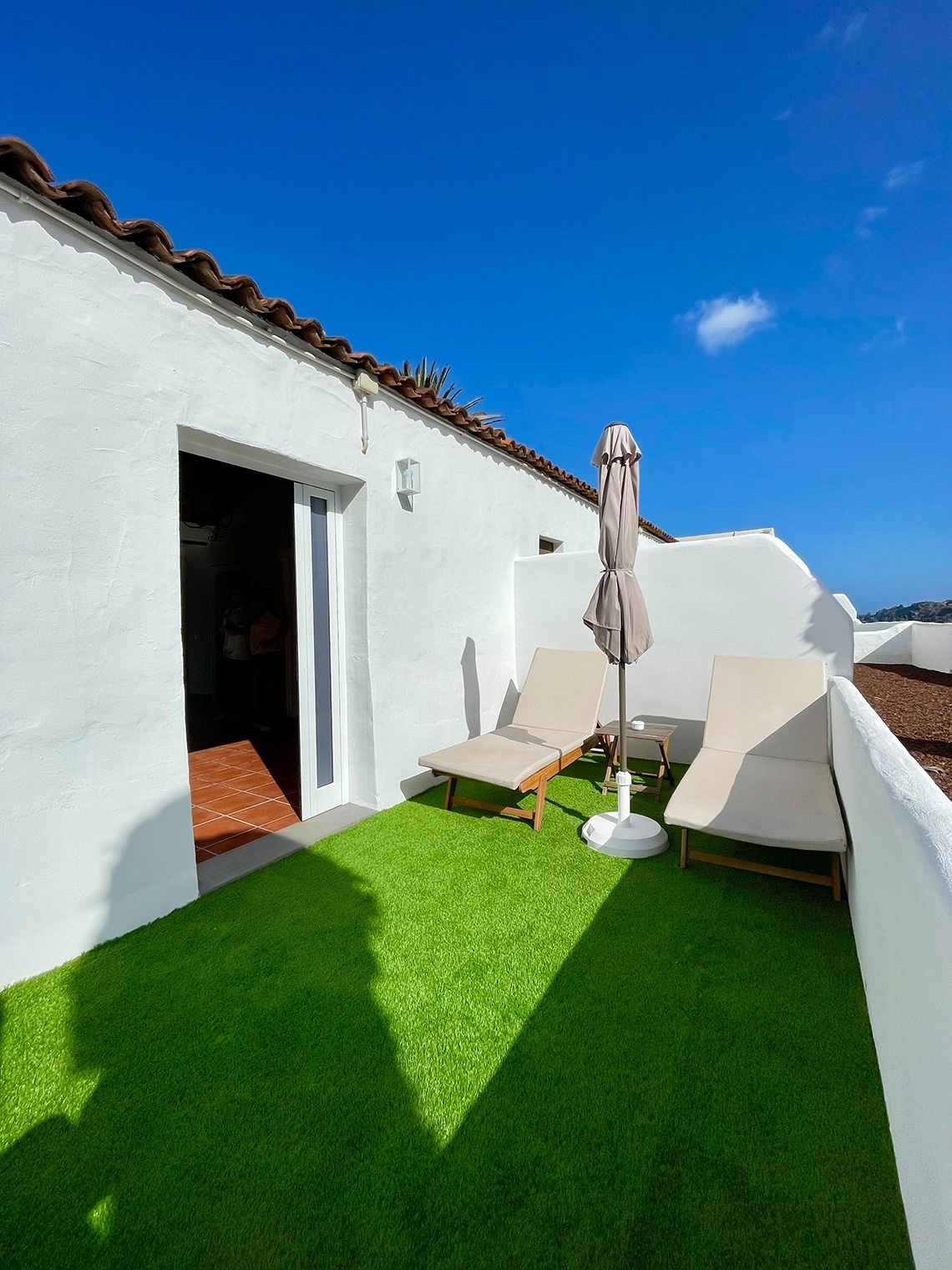 two lounge chairs and an umbrella on a patio