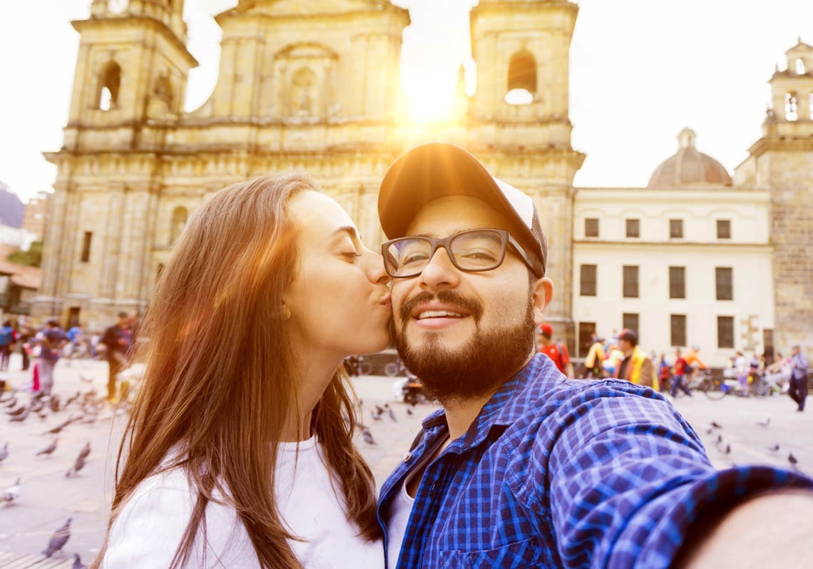 a woman kisses a man on the cheek in front of a building