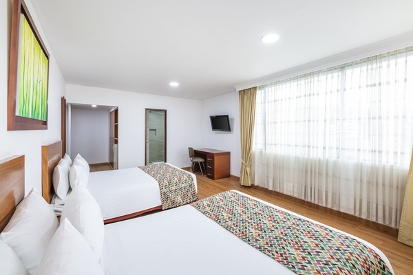 a hotel room with two beds and a flat screen tv