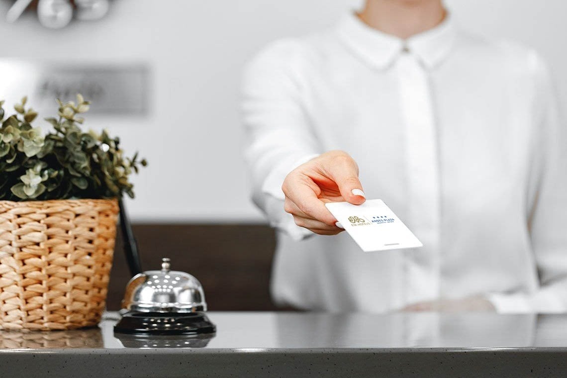 una mujer sostiene una tarjeta de presentación con el logotipo del hotel