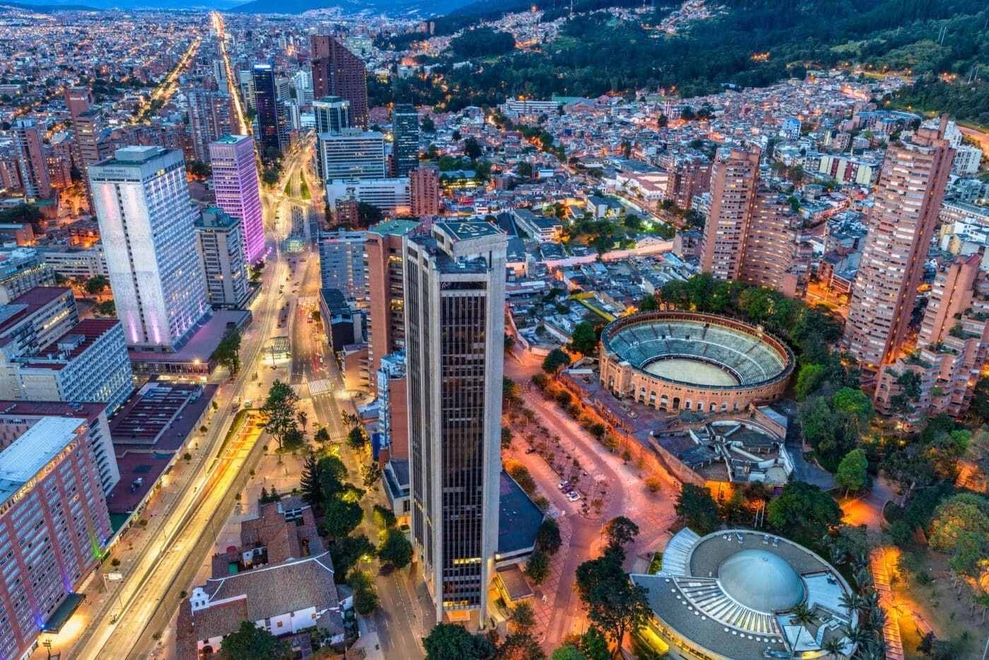 an aerial view of a city at night with a stadium in the middle
