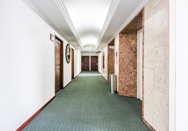 a hallway with green carpet and a clock on the wall