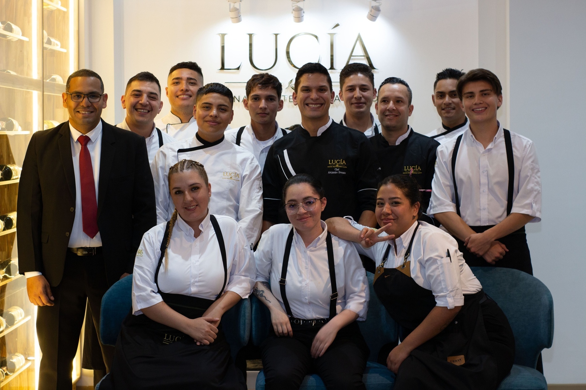 un grupo de personas posando para una foto frente a una pared que dice lucia